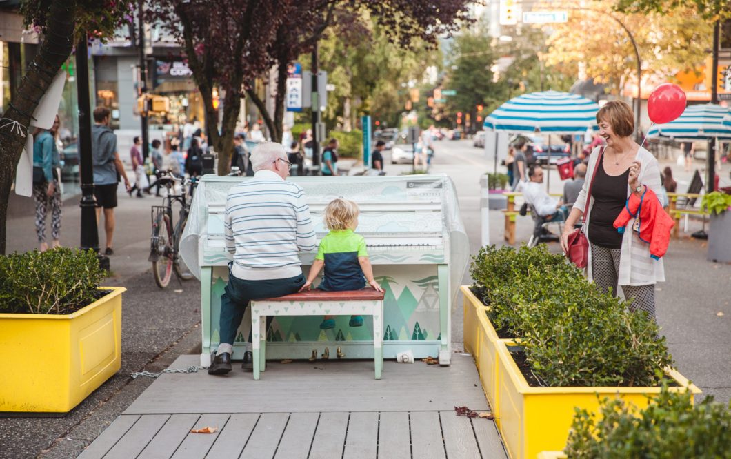 Grandparents with their grandchild at an outdoor piano in Vancouver, BC